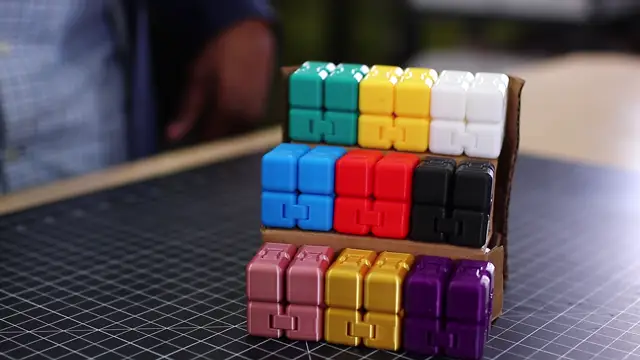 A folded cardboard stand holding rows of colorful toy cubes.
